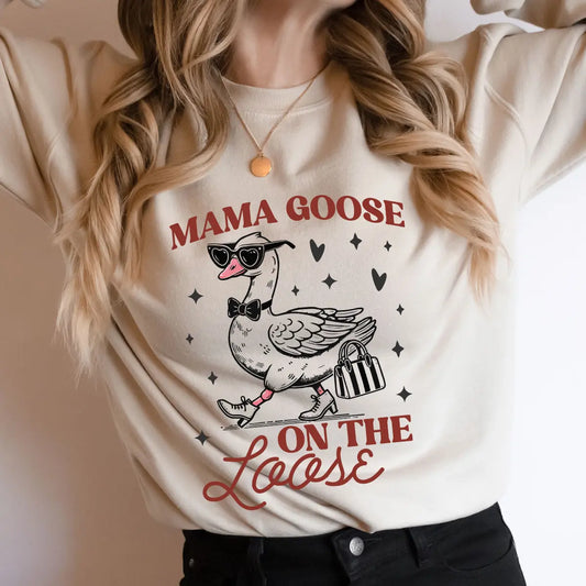 Woman wearing a cream shirt with the Mama Goose On The Loose graphic – a stylish goose with glasses and heels, featuring DTF Transfers ready to press.