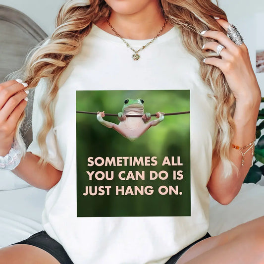 DTF Transfers ready to press – green frog hanging on rope with “Sometimes all you can do is just hang on” text. Funny, motivational design for tees and gifts.