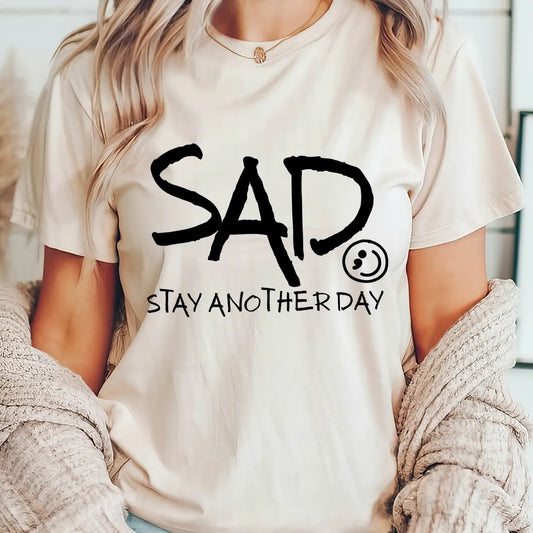 DTF Transfers ready to press – black handwritten-style “SAD Stay Another Day” mental health awareness design on neutral shirt, supporting suicide prevention.