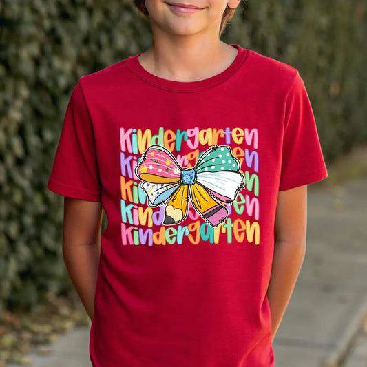 Red T-shirt with “Kindergarten” DTF transfer design featuring layered colorful text and a big multicolor patterned bow in the center.