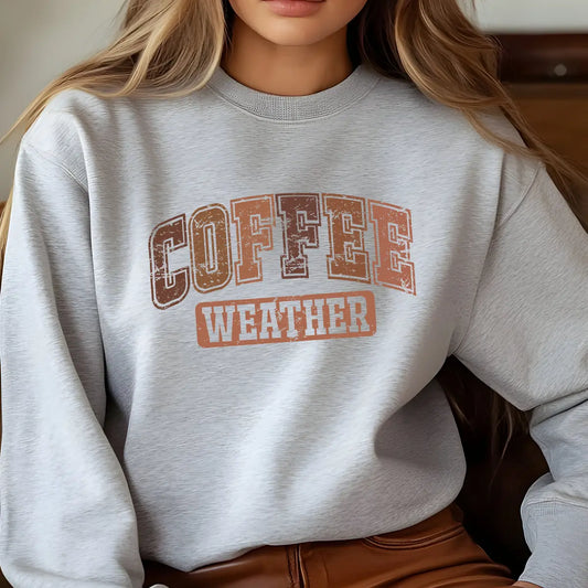 Gray sweatshirt with “Coffee Weather” DTF transfer design in large vintage collegiate lettering in warm fall colors.