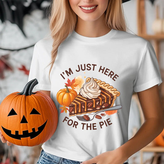 White t-shirt with "I’m Just Here for the Pie" DTF transfer design featuring pumpkin pie slice with whipped cream, pumpkins, and autumn leaves—perfect for Thanksgiving.