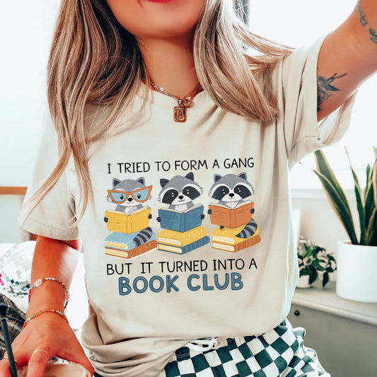 Softcream t-shirt with colorful “I Tried to Form a Gang But It Turned Into a Book Club” DTF transfer design featuring reading raccoons.