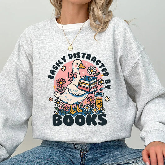 Ash grey sweatshirt with “Easily Distracted by Books” DTF transfer design featuring a cute goose, books, and floral accents—ideal for readers.