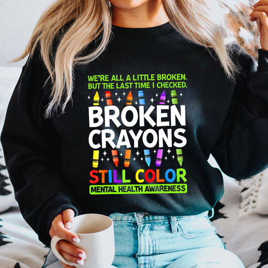 Black sweatshirt with colorful “Broken Crayons Still Color” mental health awareness DTF transfer design featuring bright crayons and motivational text.
