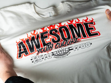 Hands stretching a T-shirt with a bold “AWESOME” DTF transfer print to show DTF transfer durability and long-lasting color.
