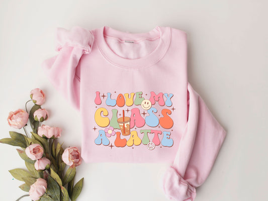 "I Love My Class A Latte" DTF transfer design on a pink sweatshirt featuring colorful retro letters, a latte cup, smiley face, peace sign, and fun classroom-themed icons.