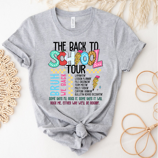 "The Back to School Tour" DTF transfer design on a gray t-shirt featuring colorful patterned letters, lightning bolts, and a playful school-themed checklist, perfect for back-to-school apparel.