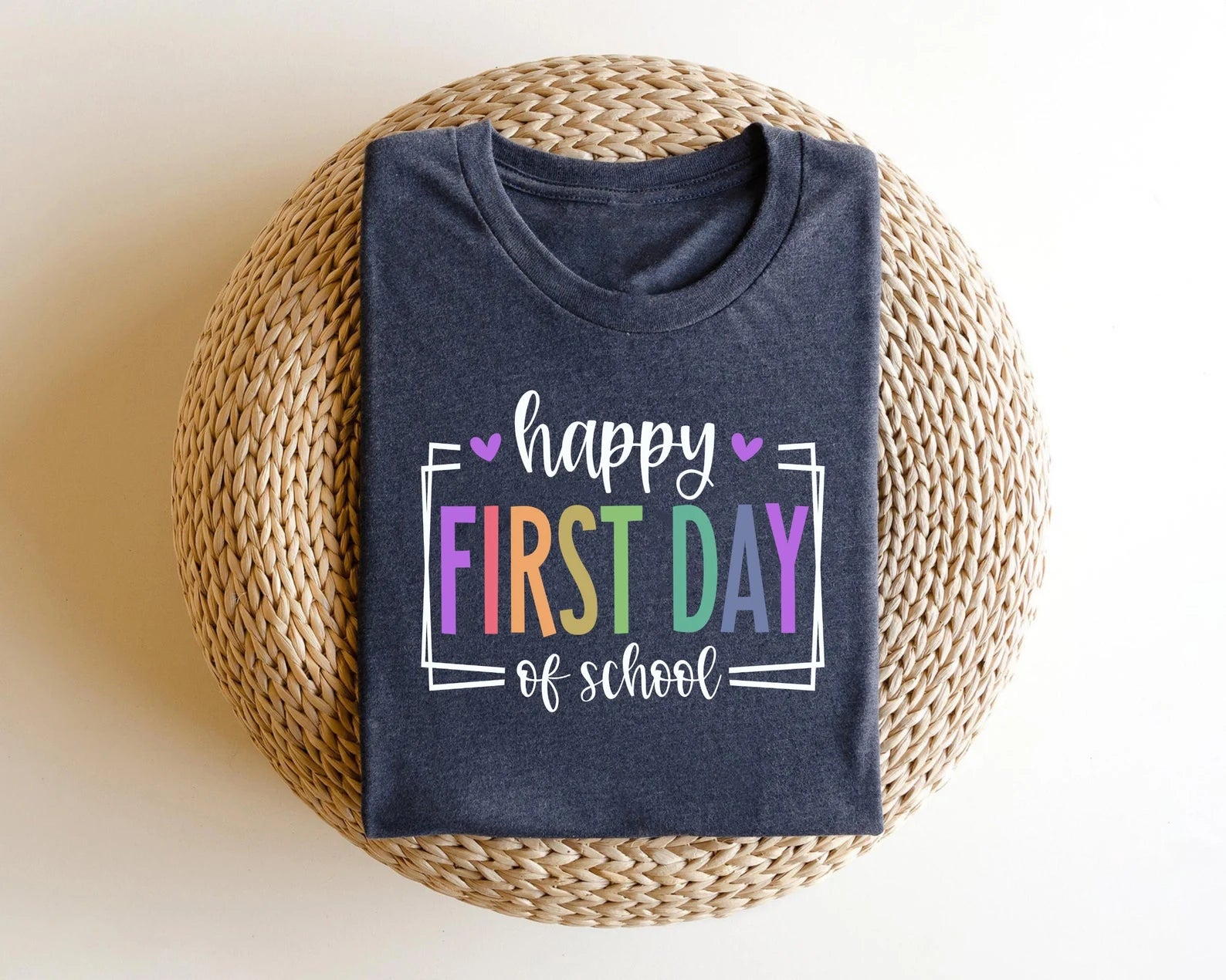 "Happy First Day of School" DTF transfer design on a dark gray t-shirt featuring bold, colorful letters framed with hearts, perfect for back-to-school apparel.