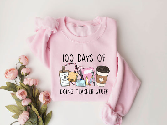 100 Days of Doing Teacher Stuff Back-to-school DTF Transfer design with coffee cup, badge, and stationery on a pink sweatshirt.