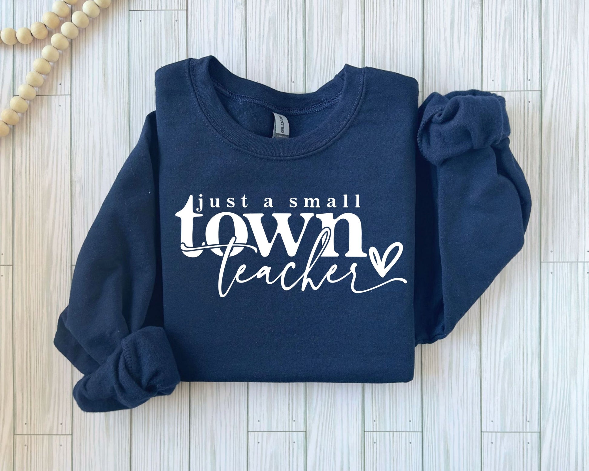 Just a Small Town Teacher DTF Transfer on a navy sweatshirt, featuring a stylish script font—ready to press on t-shirts and hoodies for educators.