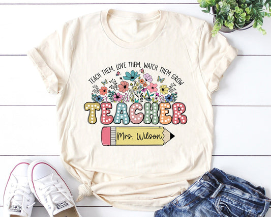 Teacher-themed DTF transfer featuring floral designs, colorful typography, and a customizable pencil for personalizing teacher names. Perfect for heat-pressed t-shirts.