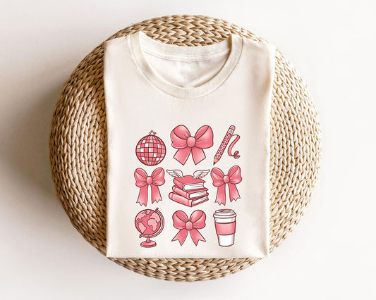 Beige sweatshirt with a pink teacher-themed DTF transfer featuring bows, books, a globe, and a coffee cup.