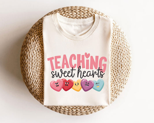 Beige sweatshirt with "Teaching Sweet Hearts" design featuring colorful candy hearts with cute expressions.