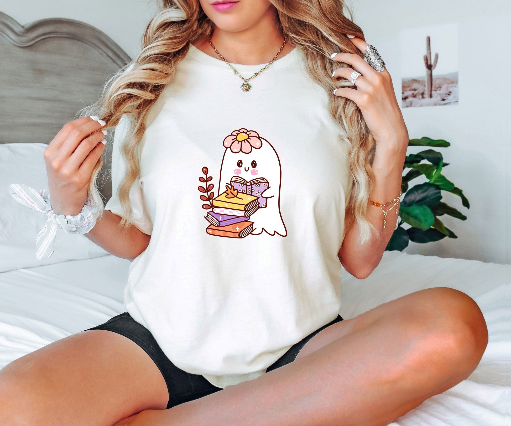 "Bookish Ghost" DTF transfer design on a white t-shirt featuring a cute ghost with a flower crown, reading a book on a stack of colorful books.