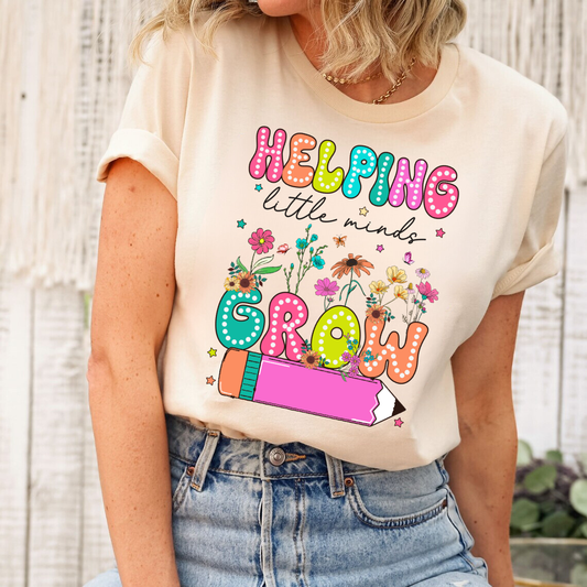 Beige t-shirt with a Helping Little Minds Grow floral and pencil-themed teacher DTF transfer, ideal for educators.