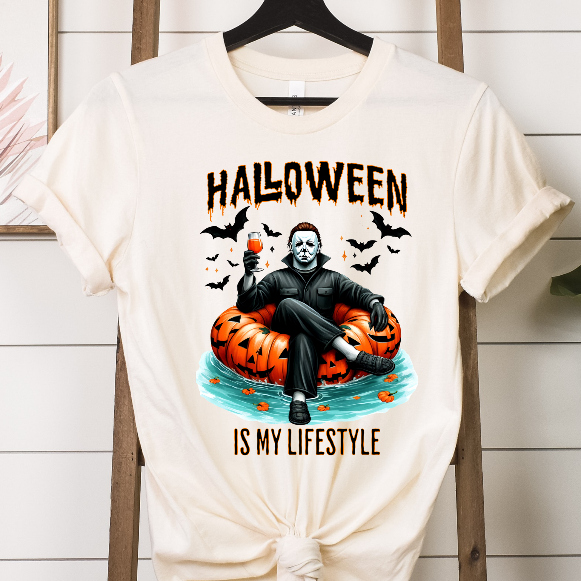 Michael Myers sitting on a pumpkin DTF transfer on a cream t-shirt