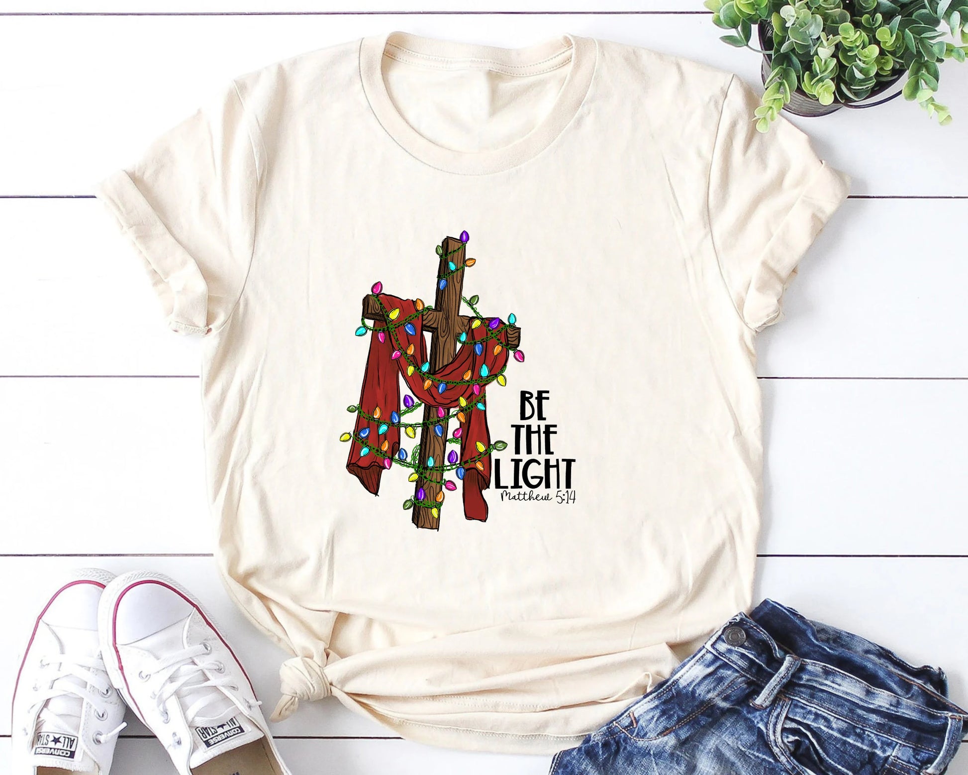 Be the Light Christmas DTF transfer design featuring a cross with colorful lights, on a t-shirt