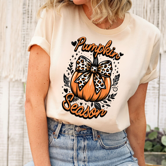 Pumpkin with leopard print bow DTF transfer on a cream-colored t-shirt.