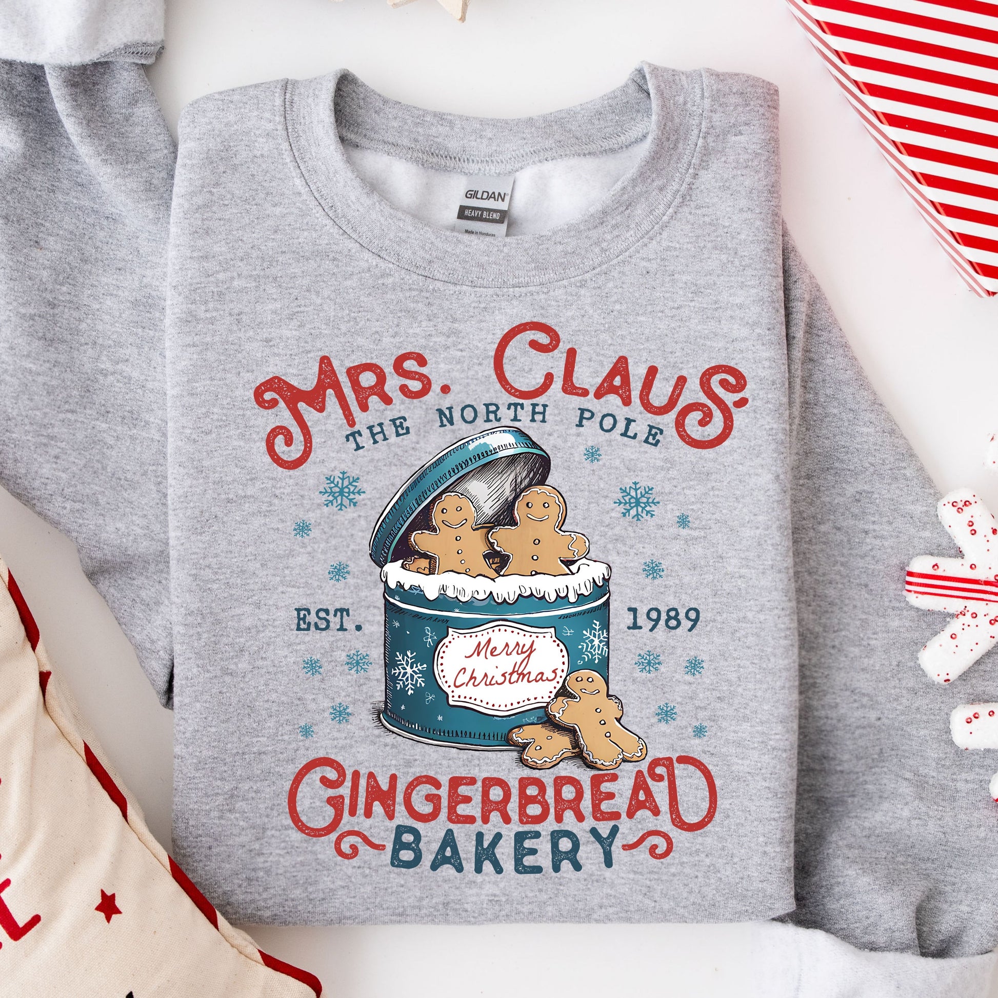 Mrs. Claus' Gingerbread Bakery DTF transfer on a gray sweatshirt, featuring gingerbread characters in a festive tin design.