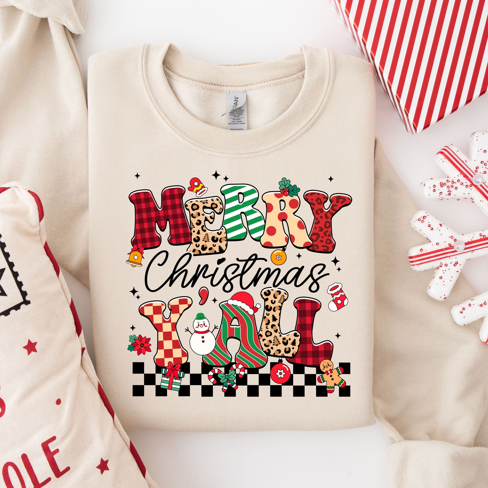 Colorful "Merry Christmas Y'all" DTF transfer on a beige sweatshirt, adorned with leopard and plaid patterns and cheerful holiday icons.