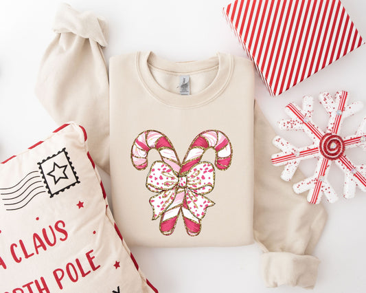 Festive Christmas DTF transfer featuring sparkling candy canes with a pink bow, displayed on a beige sweatshirt.