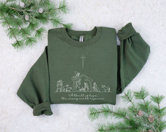 Minimalist Nativity scene silhouette on a green sweatshirt, elegantly depicting the birth of Jesus, using ready-to-press heat transfer.