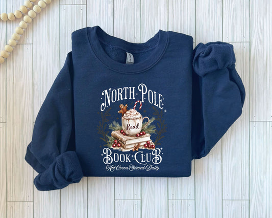 North Pole Read Book Club" DTF transfer on a navy sweatshirt, featuring a whimsical design with books and hot cocoa.