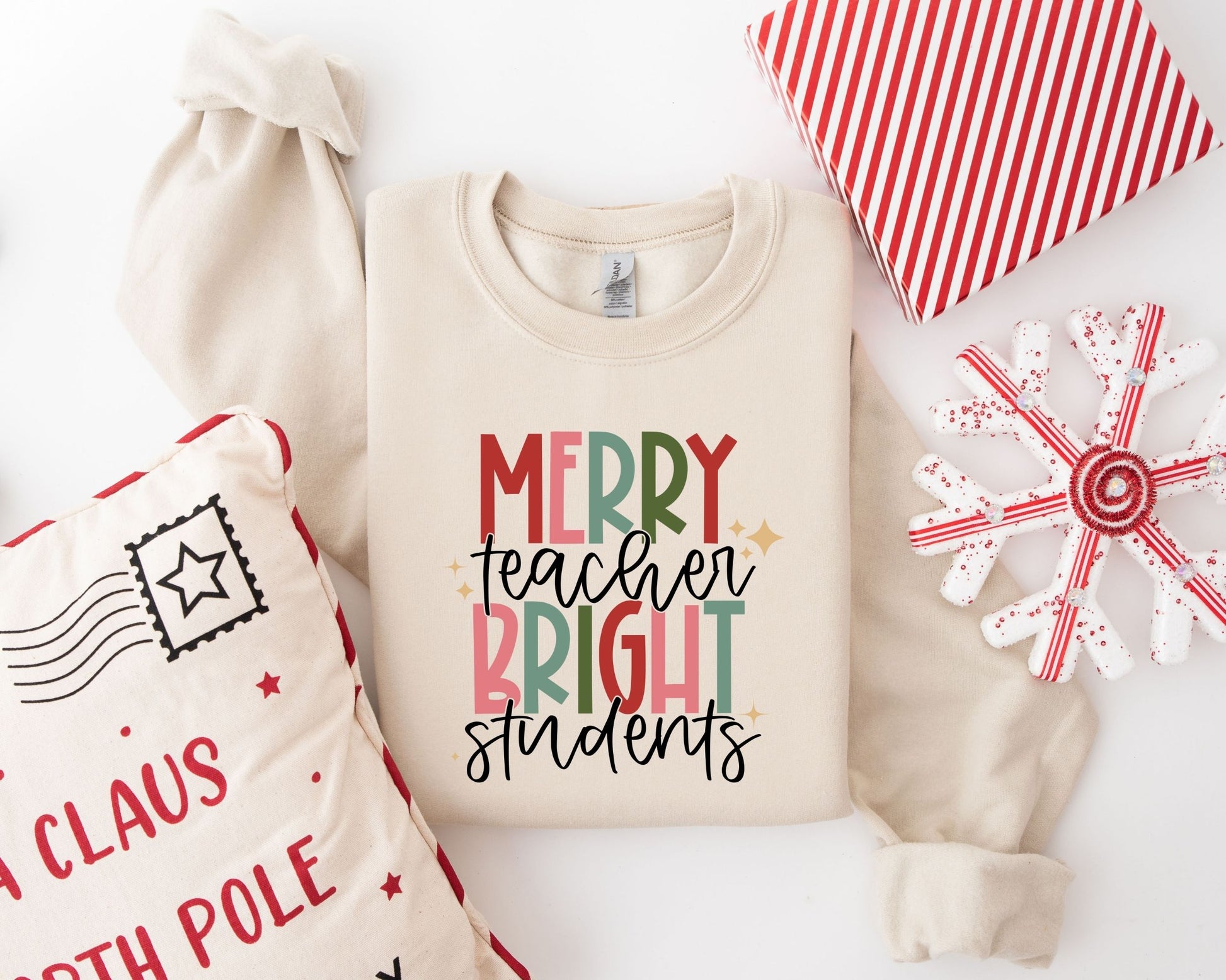 Colorful "Merry Teacher, Bright Students" Christmas ready-to-press DTF transfer on a beige sweatshirt.