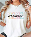 Woman wearing a white tee with pastel block letters spelling “MAMA” and a script overlay, showing off a stylish DTF Transfers ready to press design for moms.