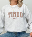 Woman wearing a gray sweatshirt with bold brown varsity-style 