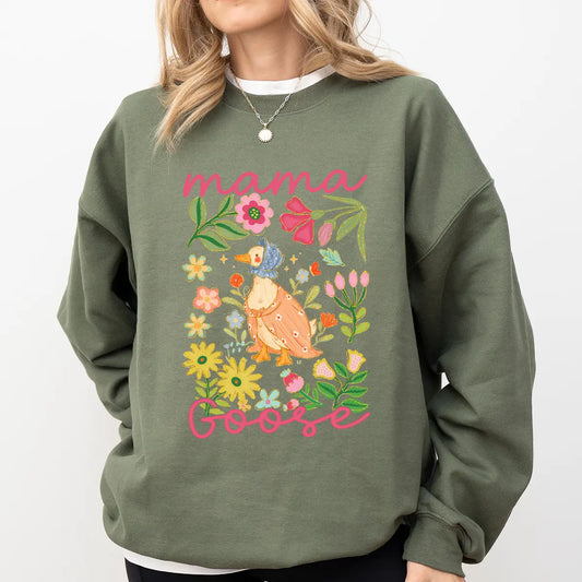 Woman in green sweatshirt featuring Mama Goose DTF Transfers ready to press – a vintage-style goose in floral garden, perfect for spring & Mother's Day shirts.