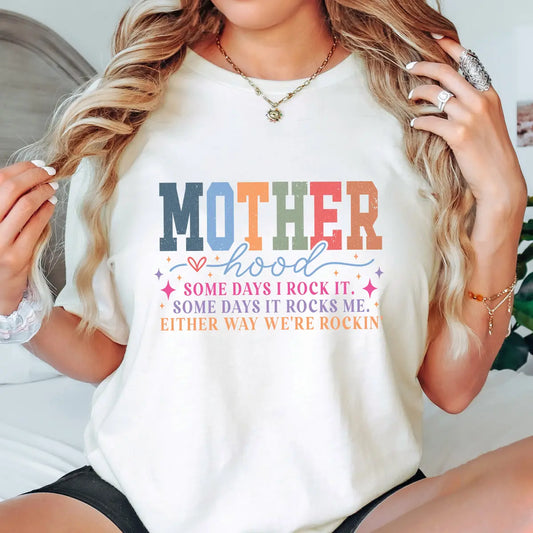 Woman wearing retro rainbow block letter “Motherhood” shirt with uplifting quote – designed using DTF Transfers ready to press.