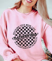 DTF Transfers ready to press with checkered grunge design and “Motherhood – Rocking This Mom Life or At Least Surviving the Mosh Pit” text on a pink sweatshirt.