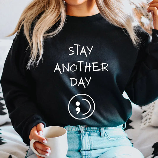 DTF Transfers ready to press – white handwritten “Stay Another Day” with semicolon symbol on black sweatshirt, clean mental health message design.