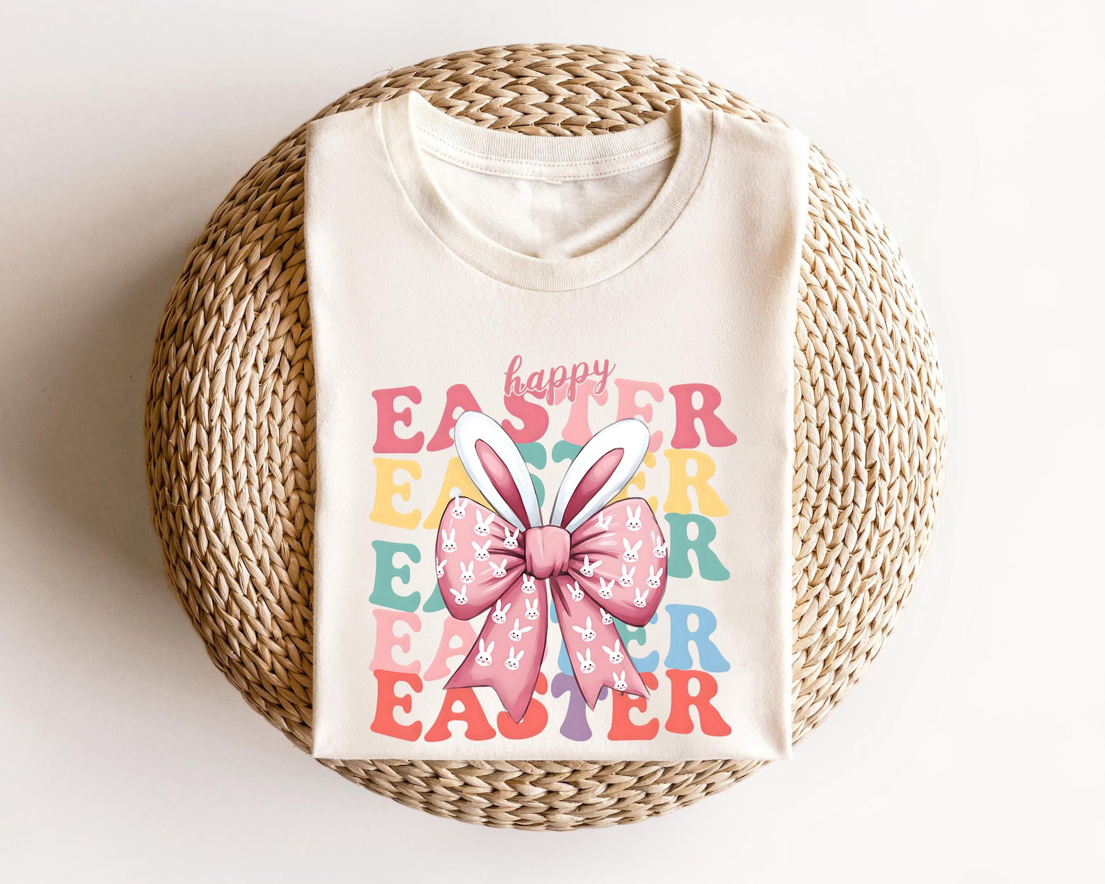 Cream-colored t-shirt featuring a "Happy Easter" retro text design with a pink bunny bow and bunny ears, perfect for Easter celebrations.