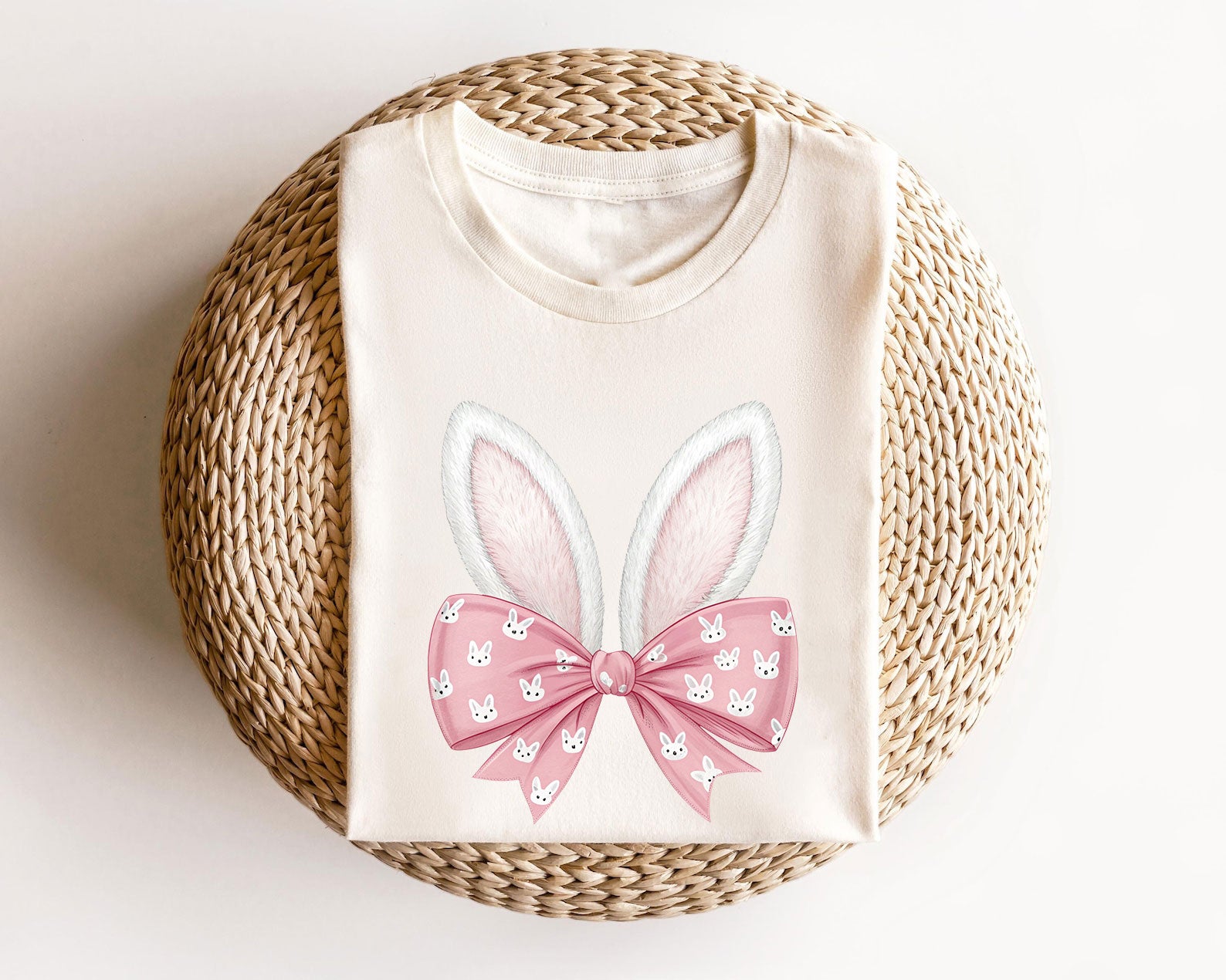 Cream t-shirt featuring white fluffy bunny ears and a pink bow with small bunny faces, perfect for Easter-themed designs.