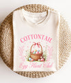 Cream t-shirt featuring a vintage Easter basket with colorful eggs, pink bow, and floral accents, perfect for Easter-themed designs.