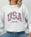 Gray sweatshirt with floral USA EST 1776 DTF transfer design in red, white, and blue colors, perfect for patriotic and feminine-themed apparel.