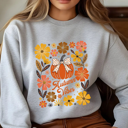Gray sweatshirt with “Autumn Vibes” DTF transfer design featuring a pumpkin with a bow surrounded by colorful fall flowers in warm autumn tones.