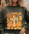 Green sweatshirt with Autumn Cross DTF transfer design featuring hand-painted cross with bow, pumpkins, and colorful fall flowers.