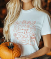 White T-shirt with “Cozy Season” DTF transfer design featuring autumn line-art icons like bows, pumpkin, scarf, coffee, boots, candle, and flowers.