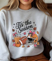 Gray sweatshirt with “Tis’ the Season” DTF transfer design featuring football, helmet with bows, iced coffee, pumpkins, and autumn leaves.