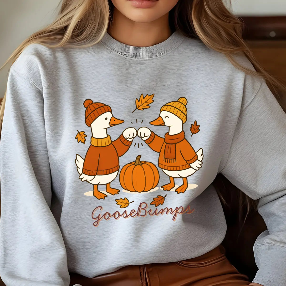 Gray sweatshirt with “GooseBumps” DTF transfer design featuring two autumn-dressed ducks fist-bumping over a pumpkin with falling leaves.
