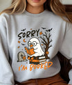 Gray sweatshirt with “Sorry I’m Booked” DTF transfer design featuring a ghost duck reading on books, with fall leaves, bats, and graveyard scene.