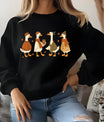 Black sweatshirt with fall-themed DTF transfer design of four ducks in cozy autumn clothing, accented with falling leaves.