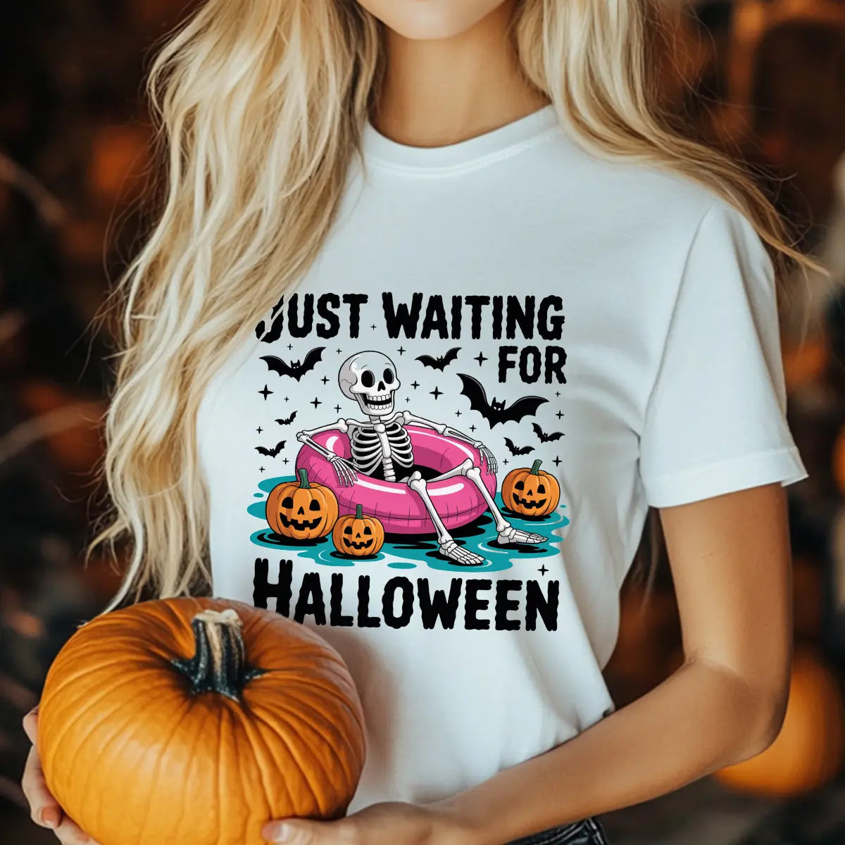 White T-shirt with “Just Waiting for Halloween” DTF transfer design featuring a skeleton in a pink pool float with pumpkins and bats.