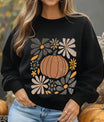 Black sweatshirt with retro-style DTF transfer design of an orange pumpkin surrounded by warm-toned autumn flowers.
