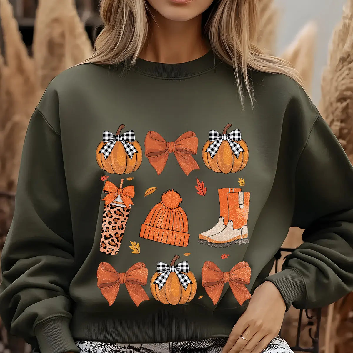 Green sweatshirt with cozy fall DTF transfer design featuring pumpkins, gingham bows, knit beanie, boots, and leopard-print tumbler, ideal for autumn apparel.