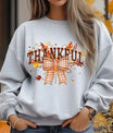 Grey sweatshirt with “Thankful” text, fall leaves, and gingham bow DTF transfer.